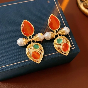 Macro shot of vintage gold earrings with pearls and red teardrop gems on a box