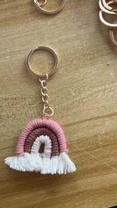 Close-up of handmade rainbow keychain with pink cotton fringes and gold metal ring
