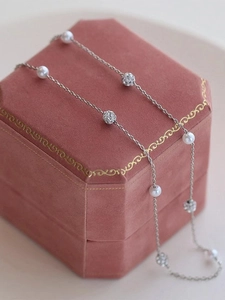 Elegant silver Y-shaped necklace with pearls and rhinestone balls on a pink velvet box