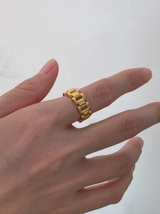 Close-up of golden hollow chain ring with heart motif on finger in a minimalist style