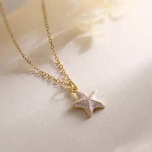 Gros plan du collier avec pendentif étoile de mer doré et incrustation blanc nacré