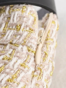 Detailed macro view of beige tweed fabric with golden threads and an invisible zipper