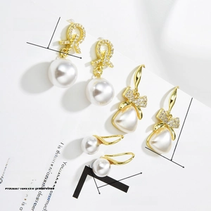 Detailed view of three baroque pearl earrings with zircon bow designs and 18K gold plating