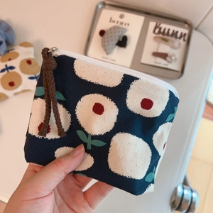 Detail of floral linen coin purse with blue dot pattern and brown braided zipper pull