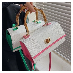 Detail of crocodile pattern handbags with bamboo handles in white, green and pink
