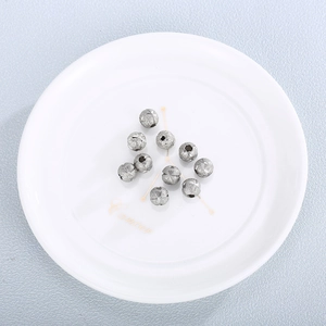 Set of 10 frosted stainless steel spacer beads with engraved texture in a white ceramic bowl
