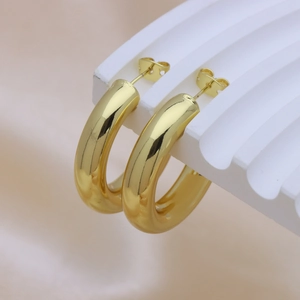 Polished 18k gold-plated twisted C-shaped earrings on a white corrugated display