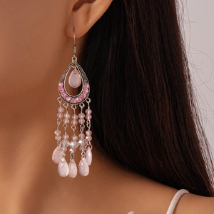 Detailed view of pink bohemian tassel earrings with rhinestones and teardrop beads on a model