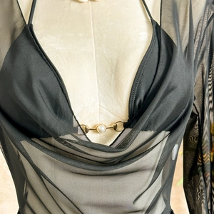 Close-up of black mesh top featuring a golden metal buckle and white pearl detail