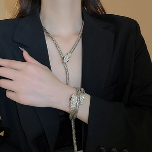 Macro shot of silver-colored snake necklace and bracelet with sparkling rhinestone details