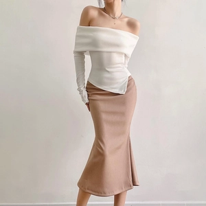 Detail view of white off-shoulder ribbed knit top with an asymmetric hemline and fishtail skirt