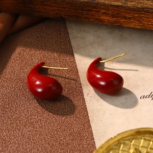 Vintage red teardrop earrings with gold posts on a rustic background for Christmas