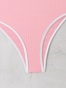 Detail of pink swimwear showing textured wavy fabric and white elastic piping edges