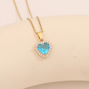 Close-up of gold heart necklace with a blue gemstone and pavé cubic zirconia accents