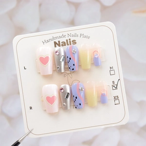 Detail of size S handmade press-on nails with pink hearts and rhinestones on card