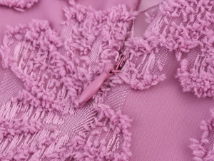 Detail view of pinkish-purple textured fabric and matching hidden zipper on the dress