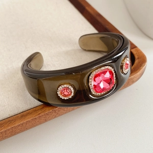 Detail of vintage olive green resin cuff bracelet with red crystal rhinestones