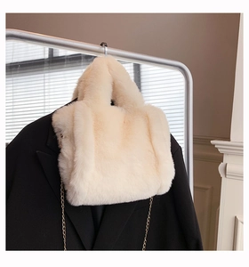 Détail du sac à main en peluche beige avec chaîne dorée sur un blazer noir chic