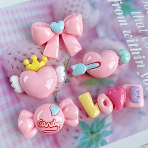 Macro detail of five pink resin DIY charms featuring heart and bow designs