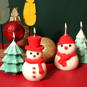 Dettaglio di candele a pupazzo di neve e albero di Natale accese con decoro festivo