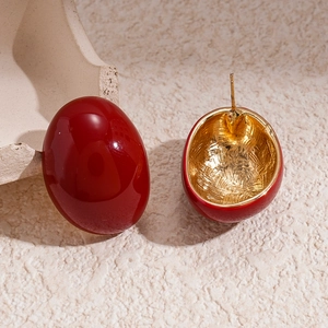 Macro detail of oval geometric red enamel studs with golden hammered metal back textures