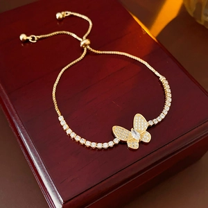 Détail du bracelet papillon en zircon doré posé sur une boîte à bijoux en bois
