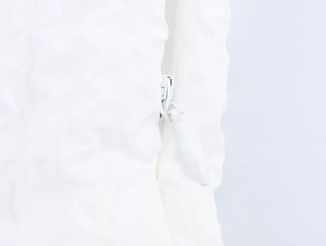 Detailed close-up of white invisible zipper on elegant embossed maxi dress fabric