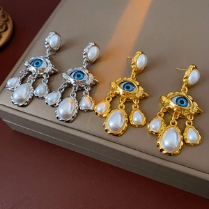 Detail view of vintage eye-shaped earrings with pearls in gold and silver finishes