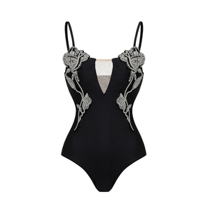 Detail of black one-piece swimsuit featuring mesh deep V-neck and 3D rhinestone flowers