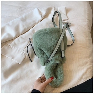 Gros plan détaillé sur la texture pelucheuse verte et la bandoulière en cuir du sac seau