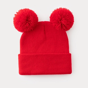 Berretto in maglia rossa da donna con due pompon di pelliccia su uno sfondo bianco puro