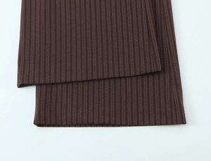 Detail of the brown trousers cuff showing clean hem and vertical white stripes pattern