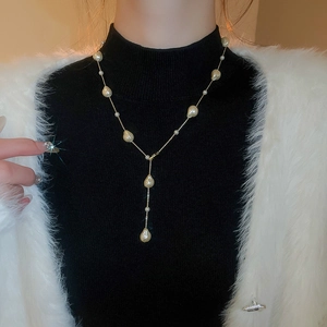 French luxury Y-shaped necklace with teardrop pearls on a black turtleneck sweater