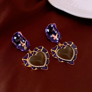 Macro shot of vintage heart earrings with purple enamel, butterfly detail, and diamond frame