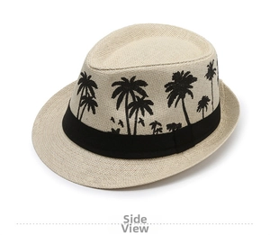 Close-up of beige straw fedora hat featuring black palm tree prints and wide band decoration
