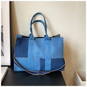 Detail of color-blocked denim tote bag with reinforced handles and adjustable strap