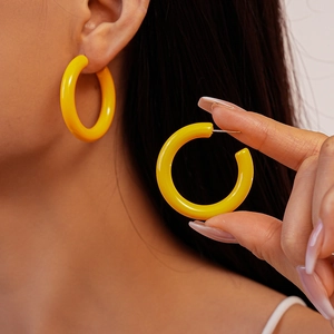 Vue détaillée de boucles d'oreilles créoles C en acrylique jaune brillant portées