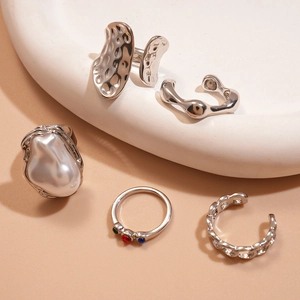 Close-up of five-piece silver ring set with pearls and zircon on a ceramic tray