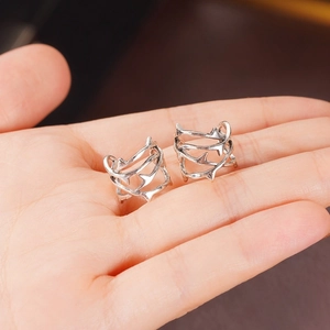 Dettaglio di un ear cuff a spine d'argento tenuto in mano con texture metallica fine