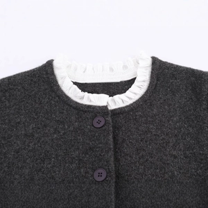 Close-up of a dark grey knit coat with white ruffled collar and purple buttons