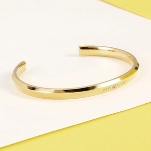 Detailed view of gold bangle with MY LOVE engraving and small zircon stone inlay
