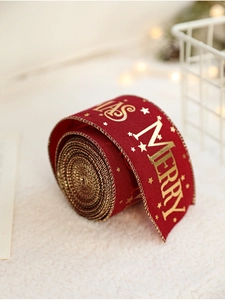 Close-up of red velvet Christmas ribbon with gold Merry Xmas lettering and stars