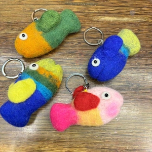 Detail view of handmade wool felt octopus keychains with metal rings on dark wood background