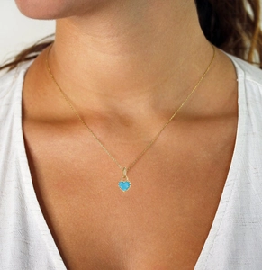 Close-up of a blue turquoise heart pendant on a delicate gold chain necklace on a model