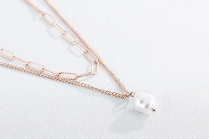 Detail of rose gold double-layered necklace with paperclip chain and baroque pearl