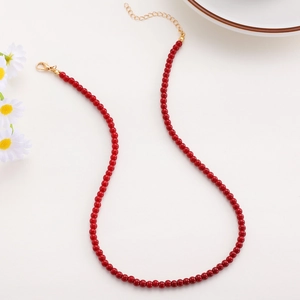 Detailed macro view of red beaded necklace with golden lobster clasp and extender chain