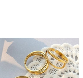 Macro detail of minimalist double-layered open gold ring on white lace with soft shadows