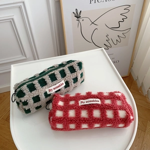 Macro shot of checkered waffle lamb wool pencil cases in green and red with soft texture