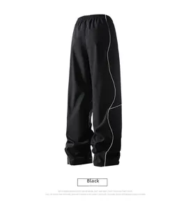 Detail view of black high-waist straight-leg trousers with white wavy side stripes