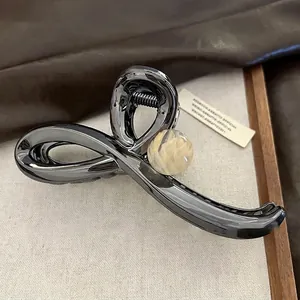 Détail macro d'une pince à cheveux en métal gris avec perle marbrée crème polie